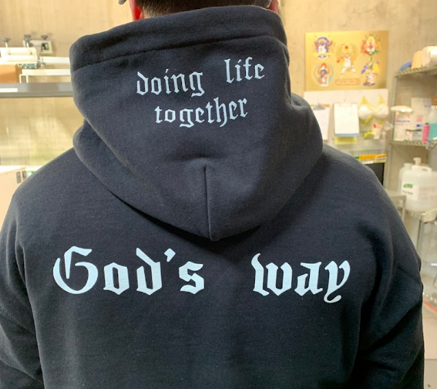 A man wearing a hoodie that says doing life together and god 's way