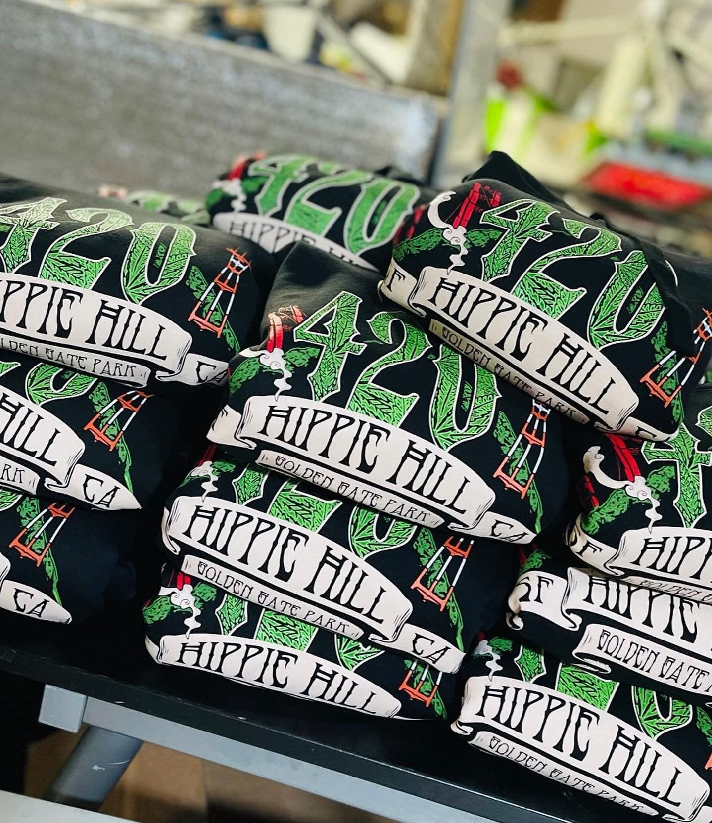 A bunch of hippie hill shirts are stacked on top of each other on a table.