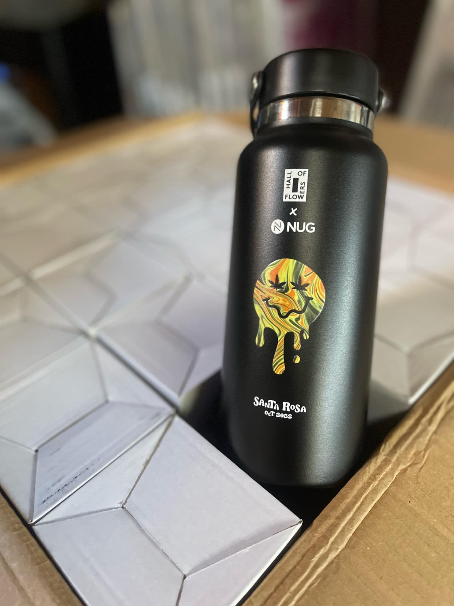 A black hydro flask is sitting on top of a cardboard box