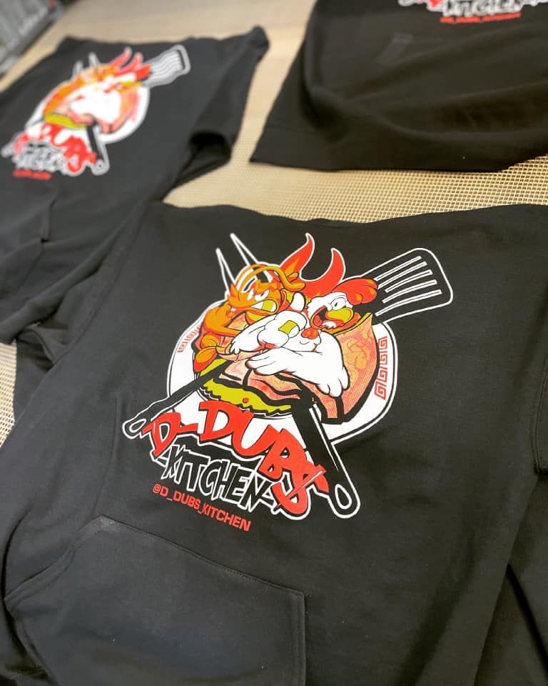 A bunch of black shirts with a picture of a chicken on them