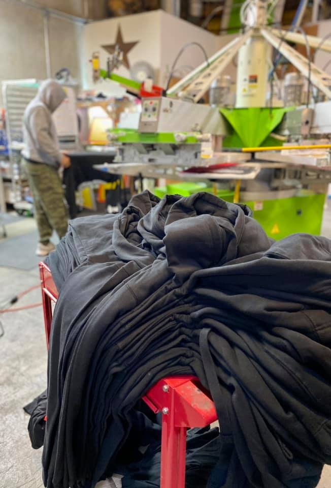 A pile of black shirts sitting on top of a table in a factory.