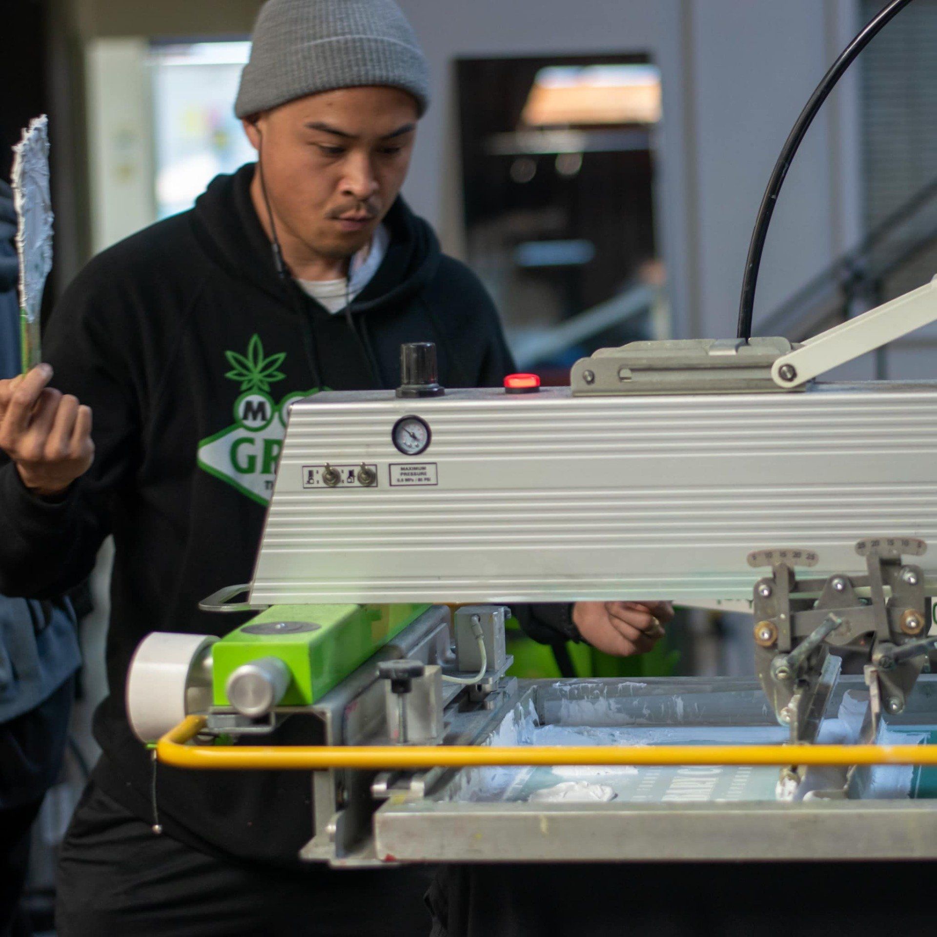 A man wearing a pineapple sweatshirt is working on a machine