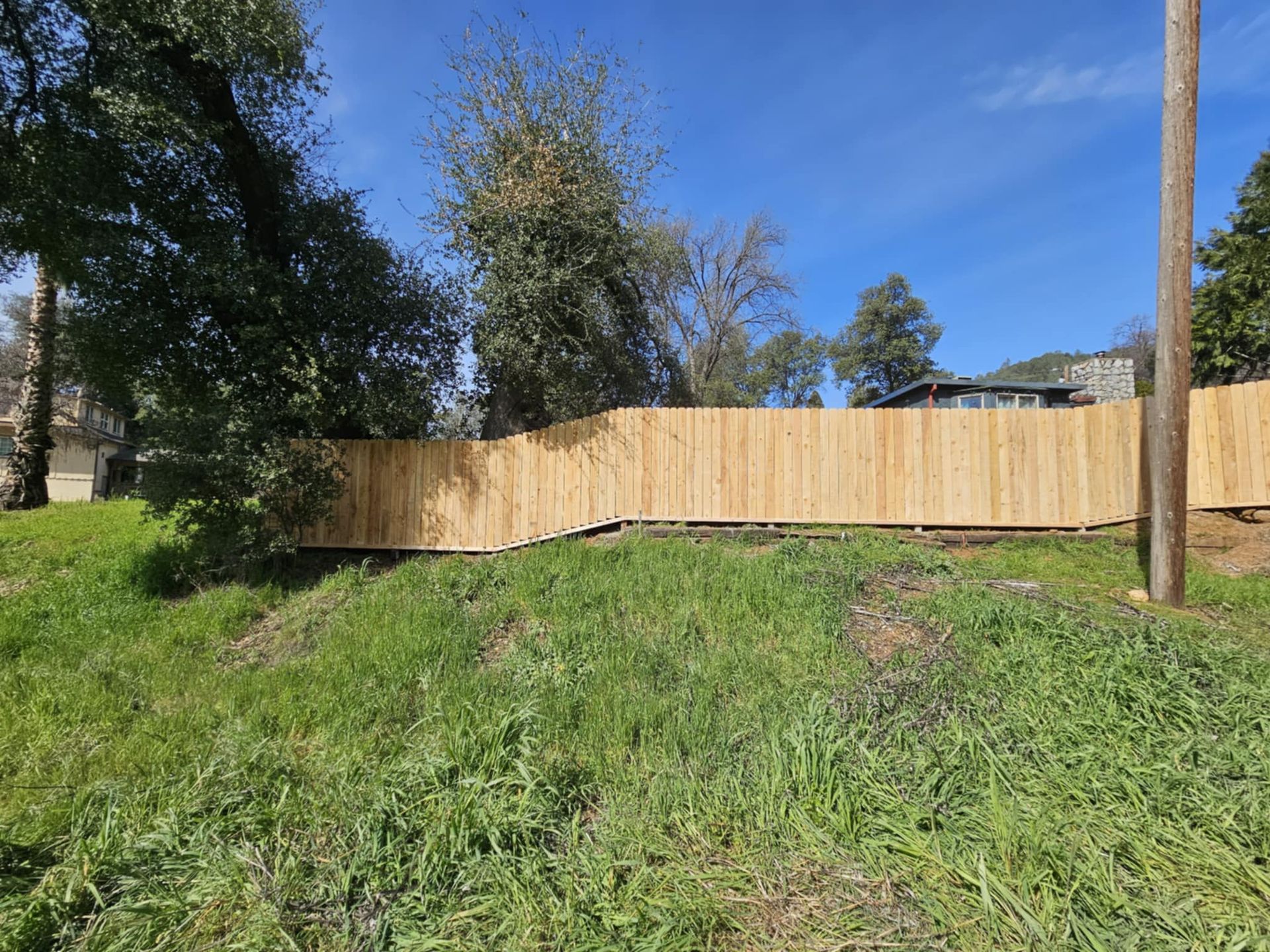 A wooden fence is in the middle of a grassy field.