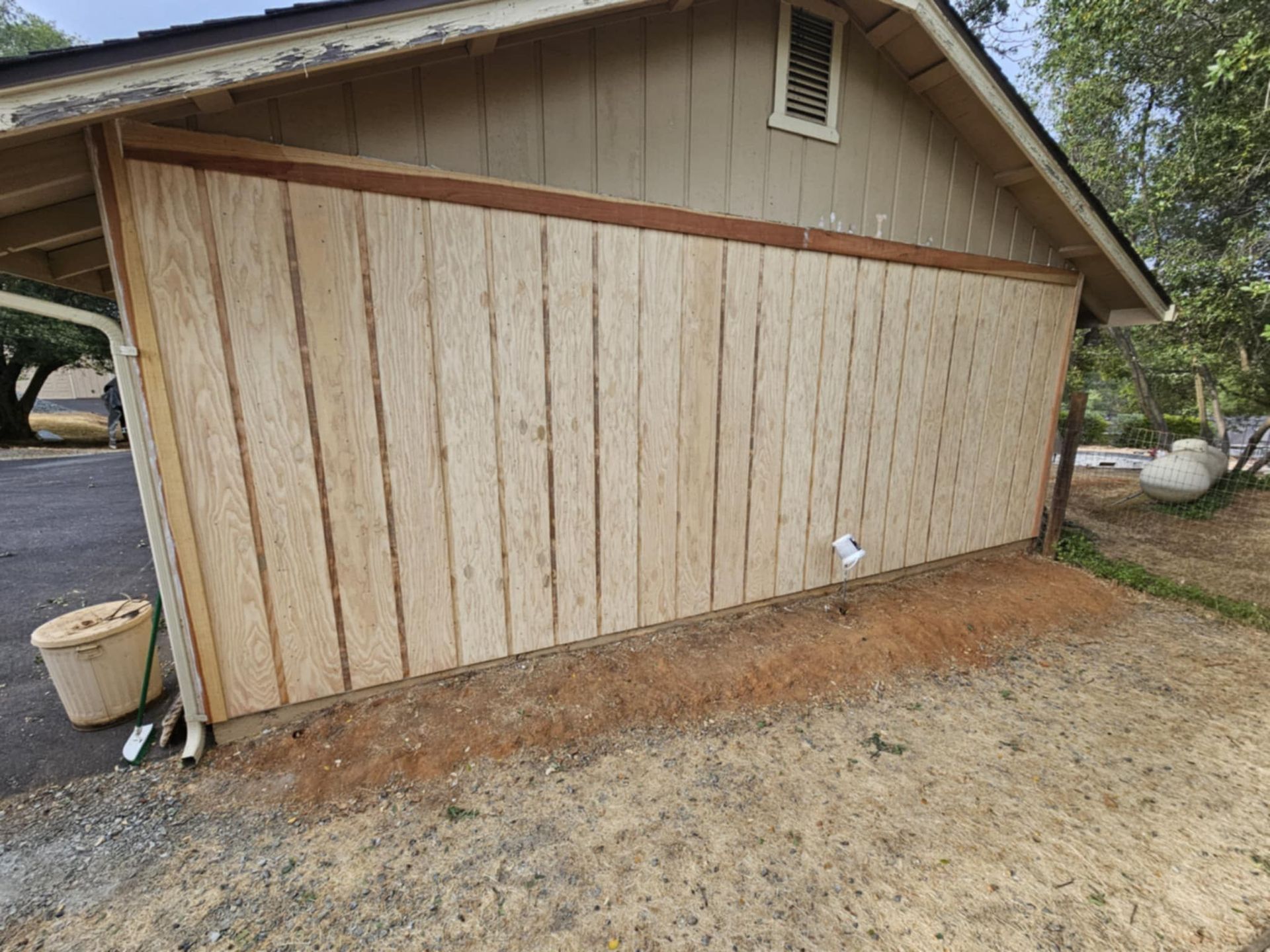 A wooden garage door is being built on the side of a house.