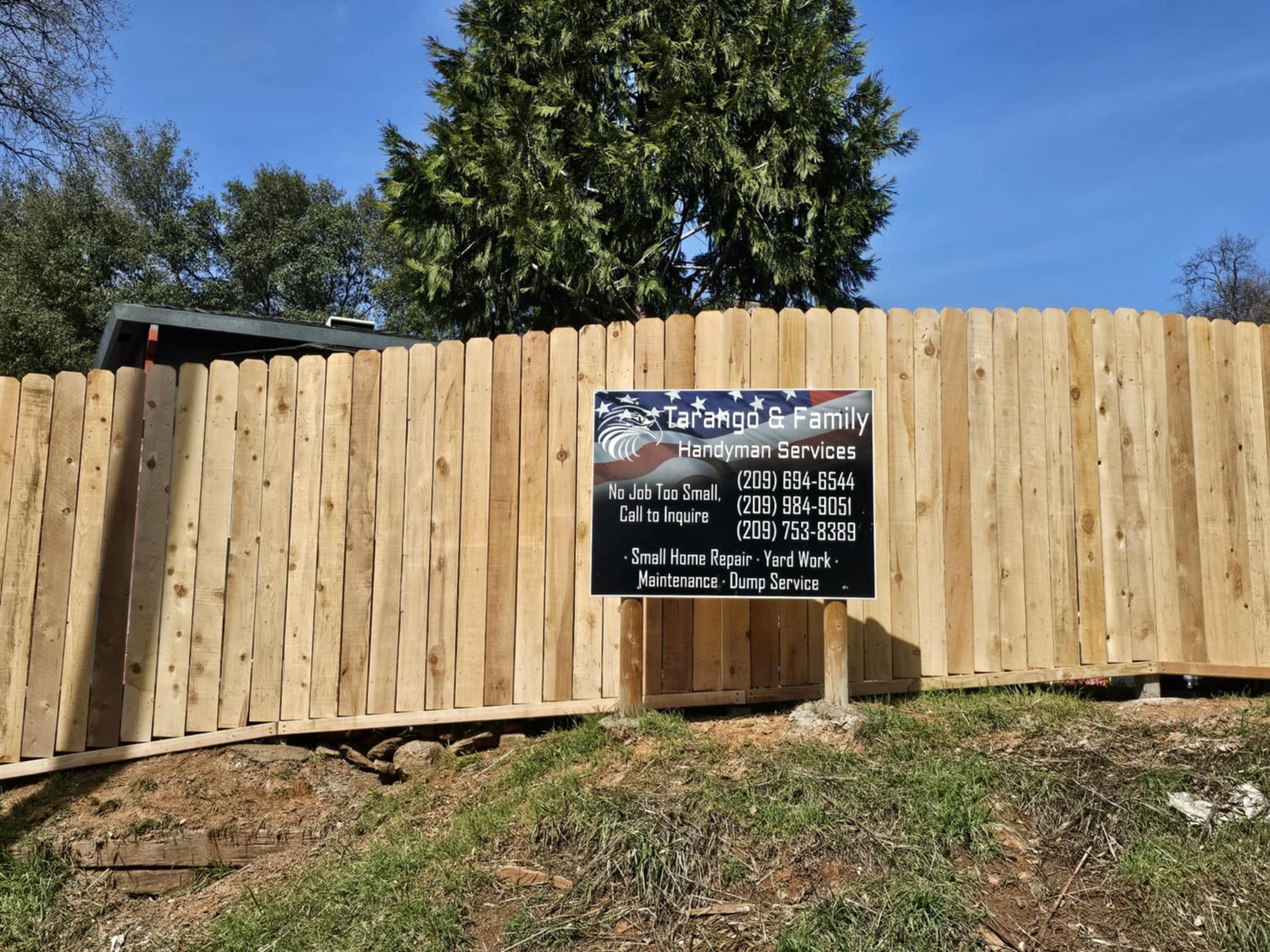 A wooden fence with a sign in front of it.