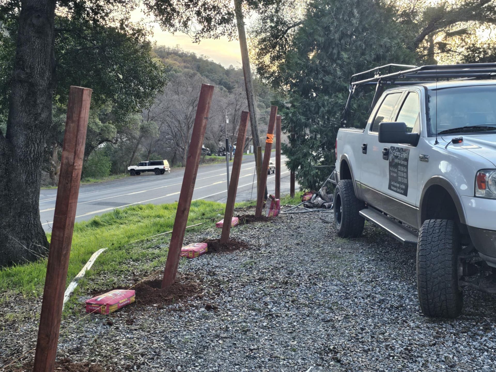 A white truck is parked next to a row of wooden posts