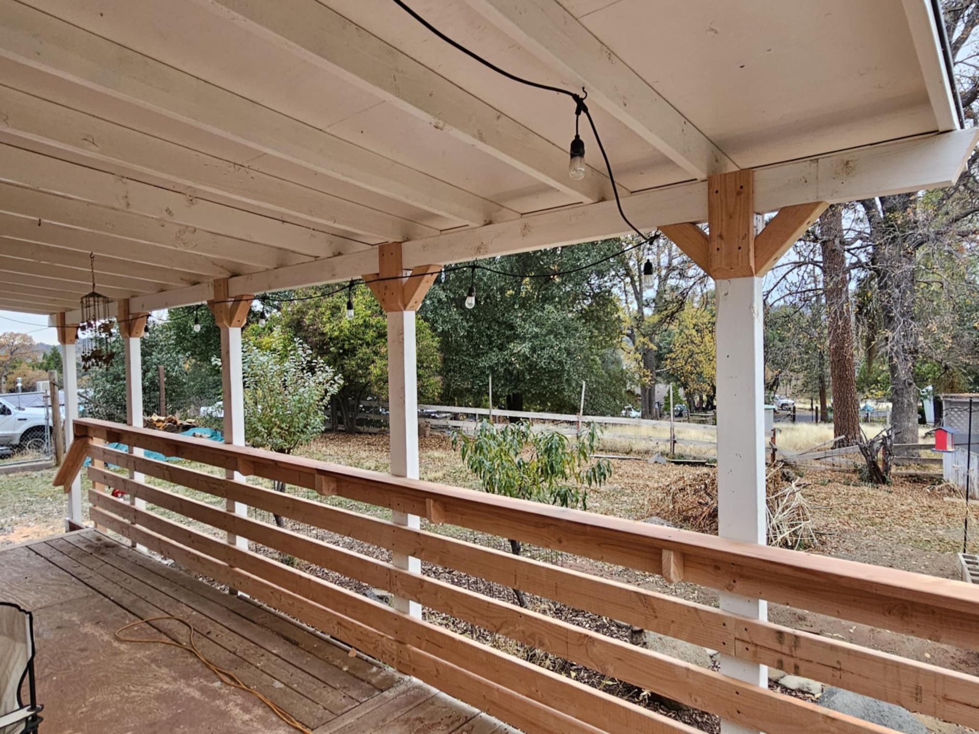 A porch with a wooden railing and a white roof.