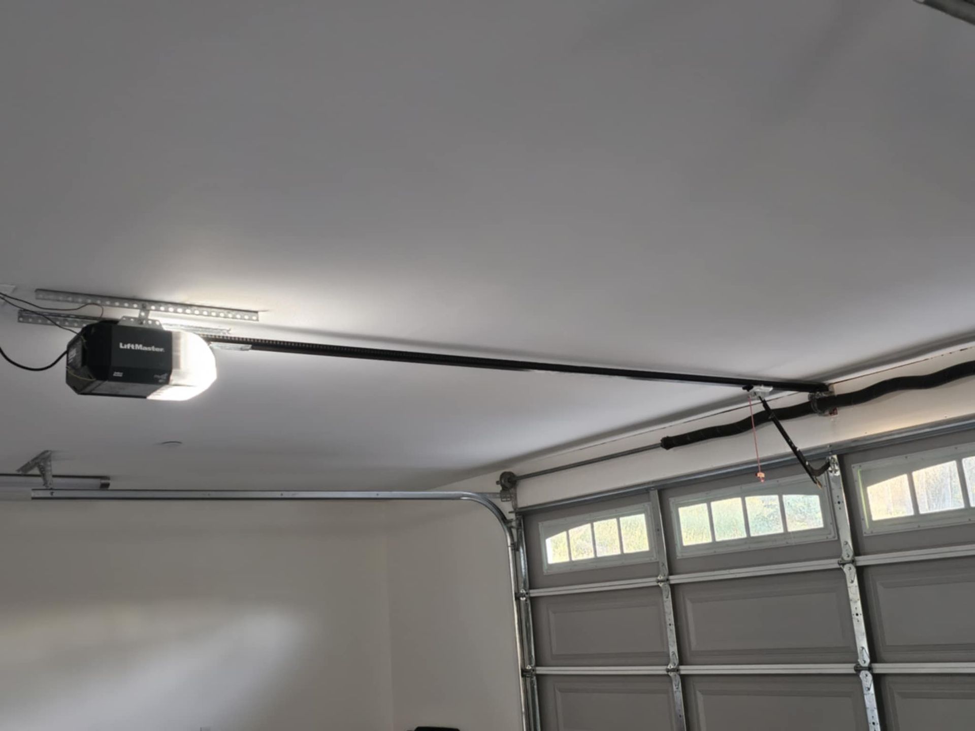 A garage door opener is hanging from the ceiling of a garage.