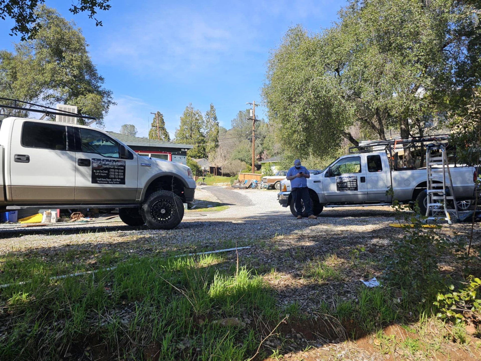 Two trucks are parked in a driveway in front of a house.