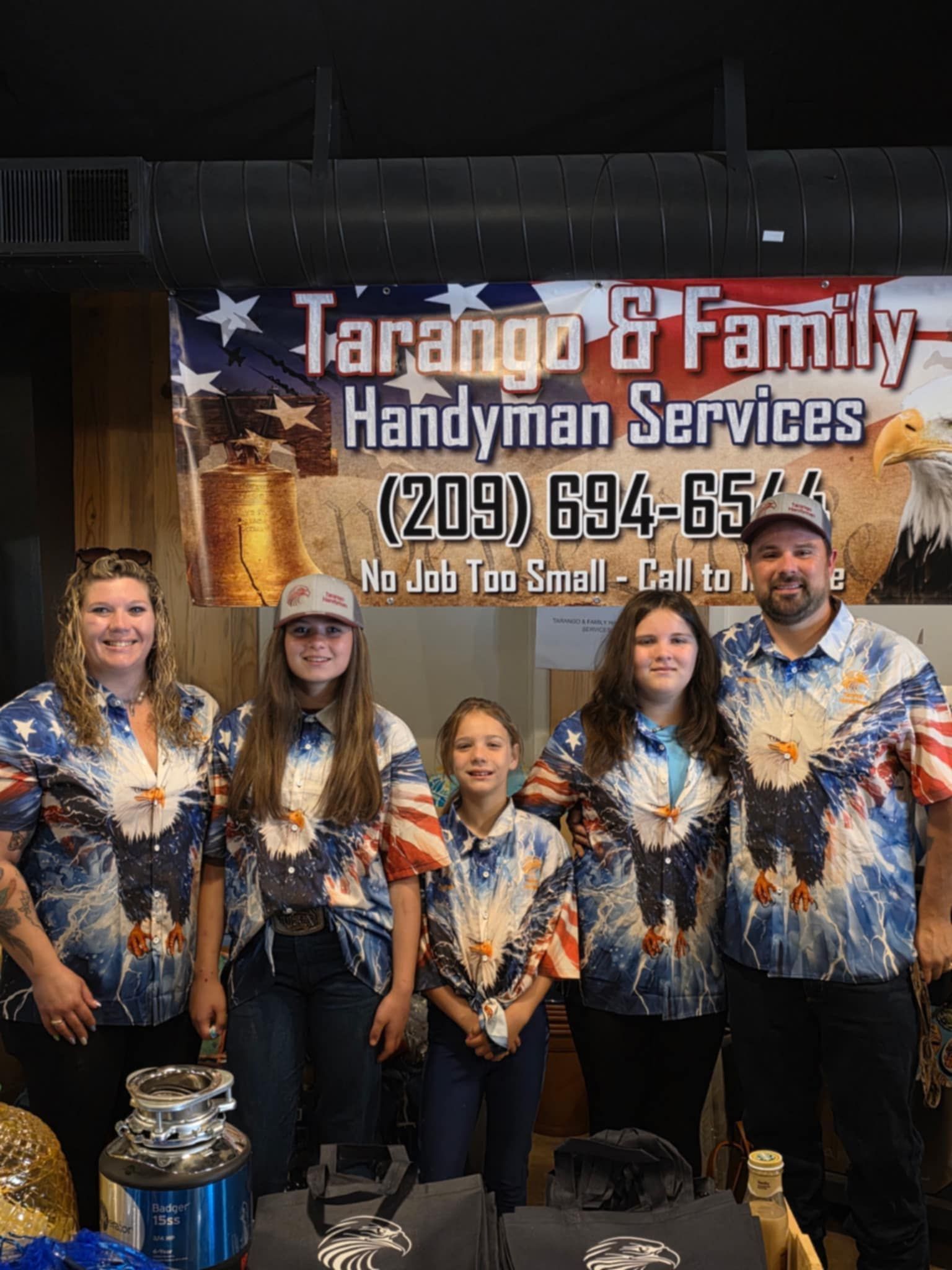 A group of people standing in front of a sign for tarango & family handyman services.