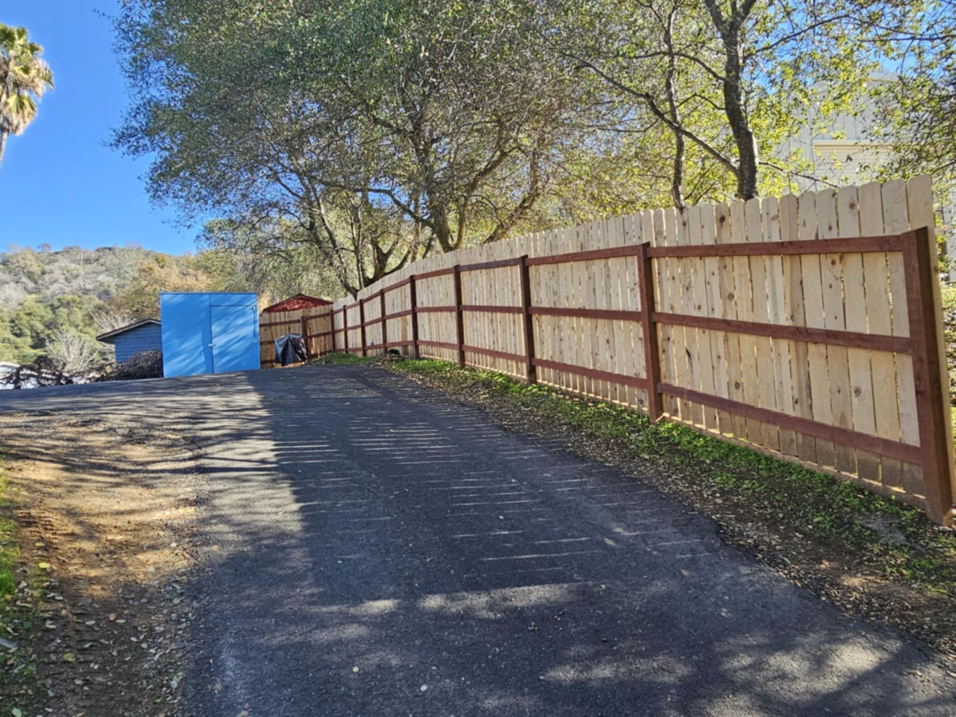 A wooden fence is along the side of a road.