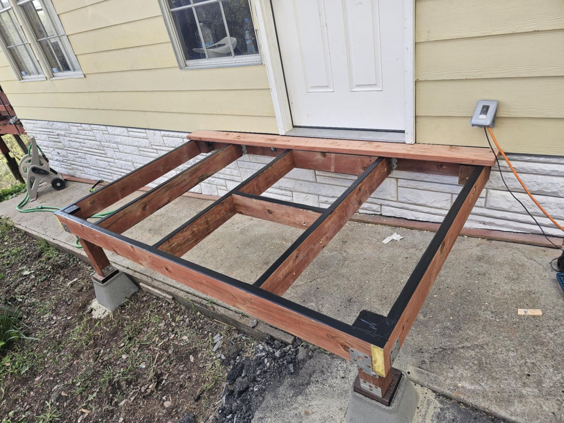 A wooden deck is being built in front of a house.