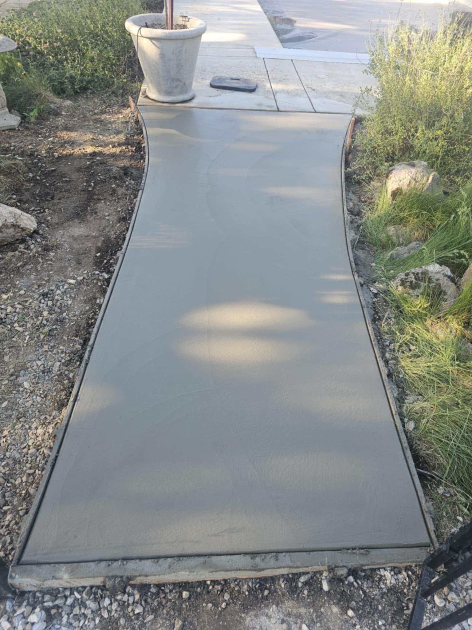 A concrete walkway is being built in a garden.