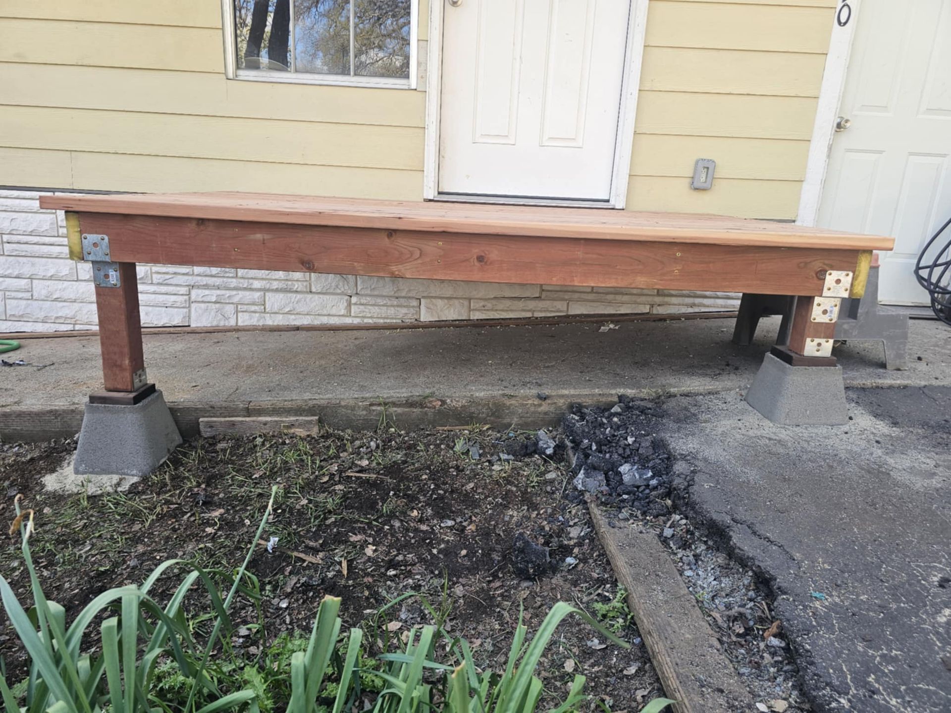 A wooden bench is sitting in front of a house.