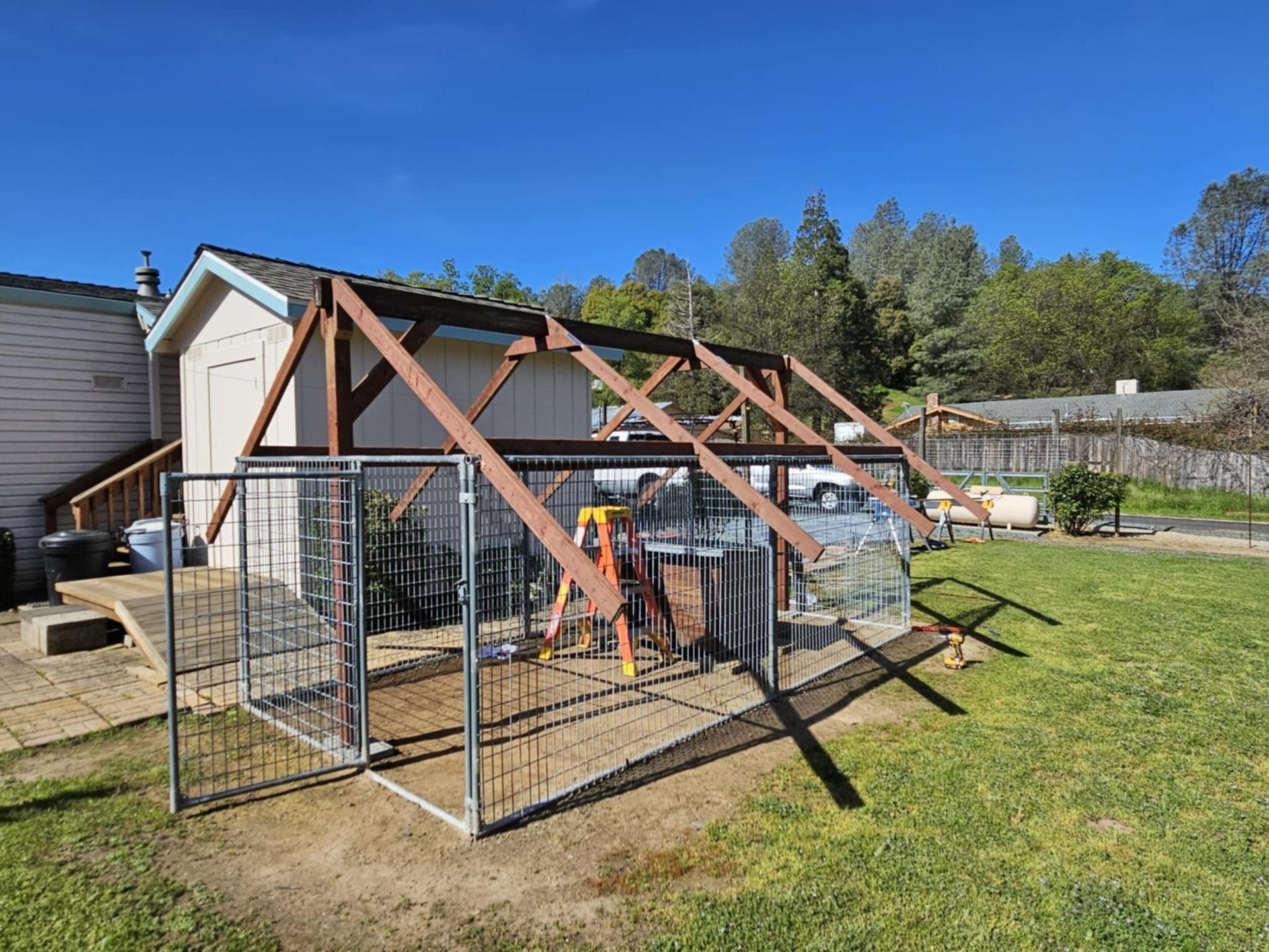 A wooden structure is being built in the backyard of a house.