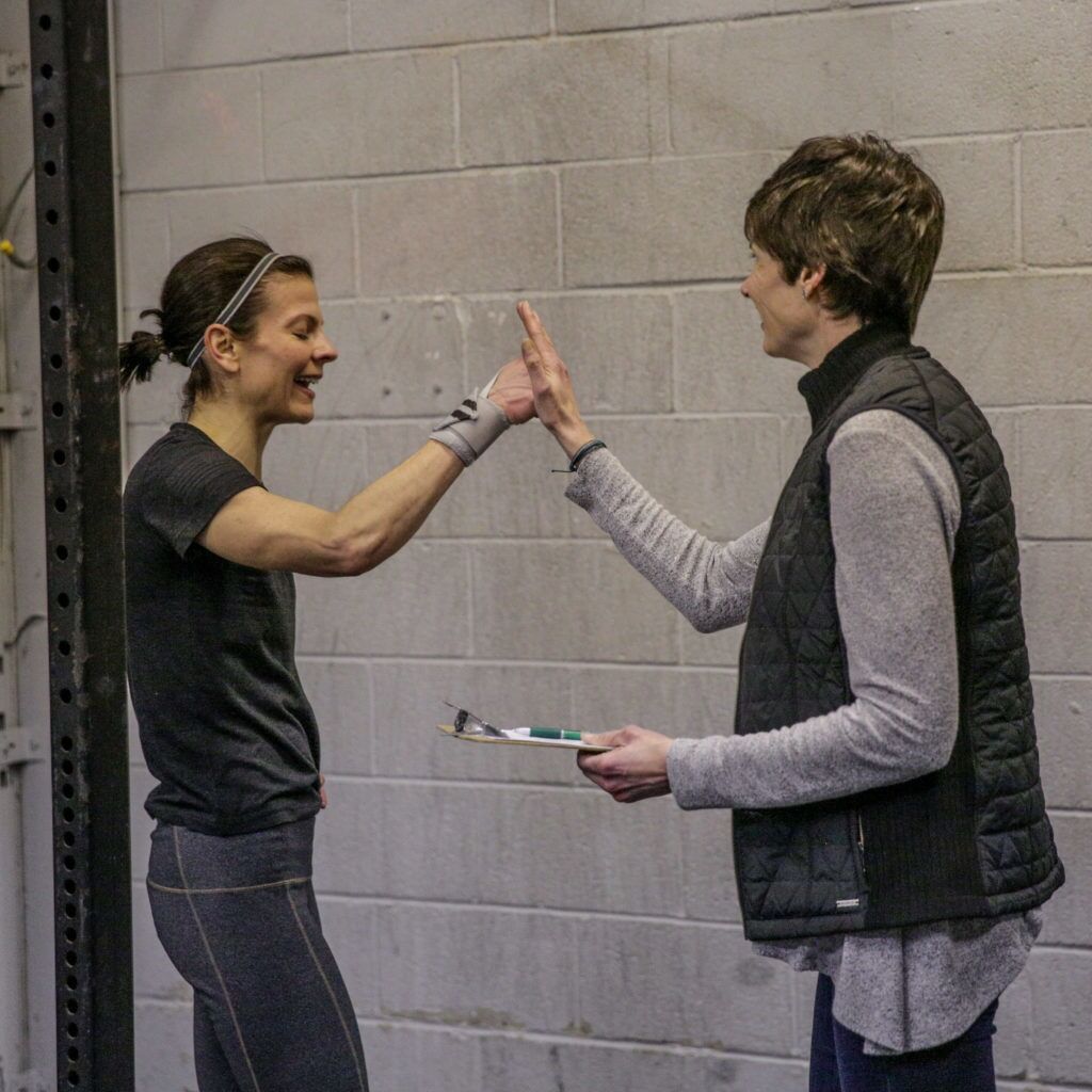 Two women giving each other a high five in front of a brick wall