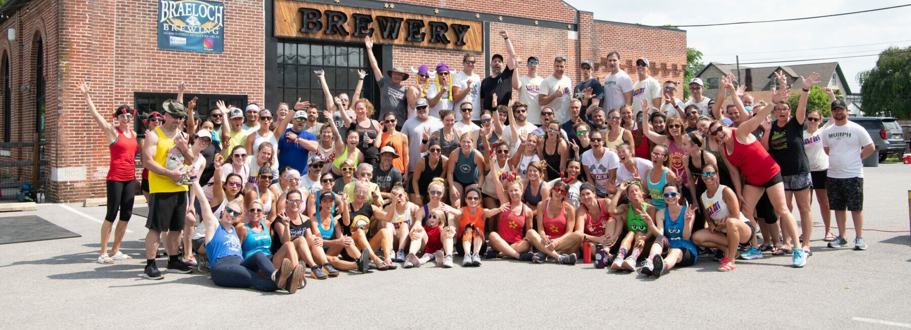 A large group of people are posing for a picture in front of a brick building.