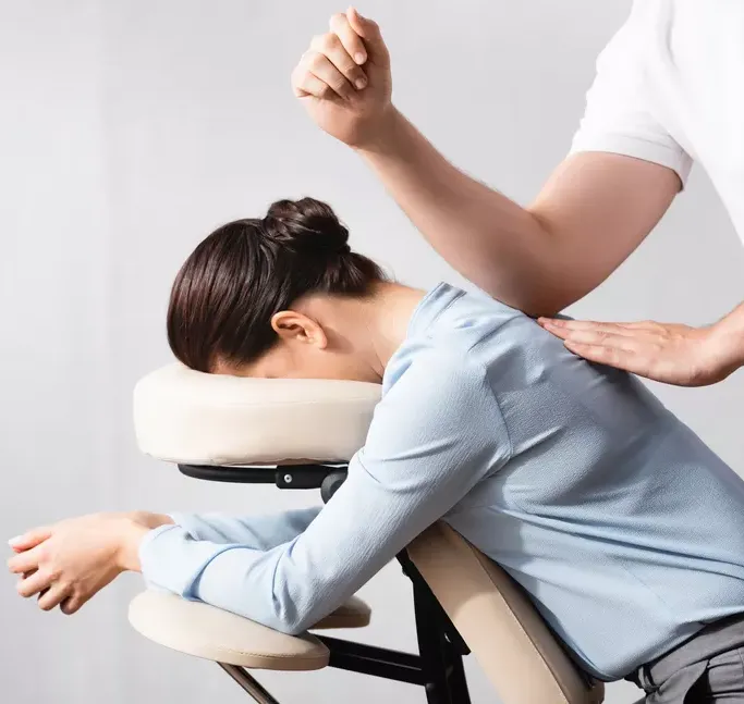une femme est assise dans une chaise recevant un massage