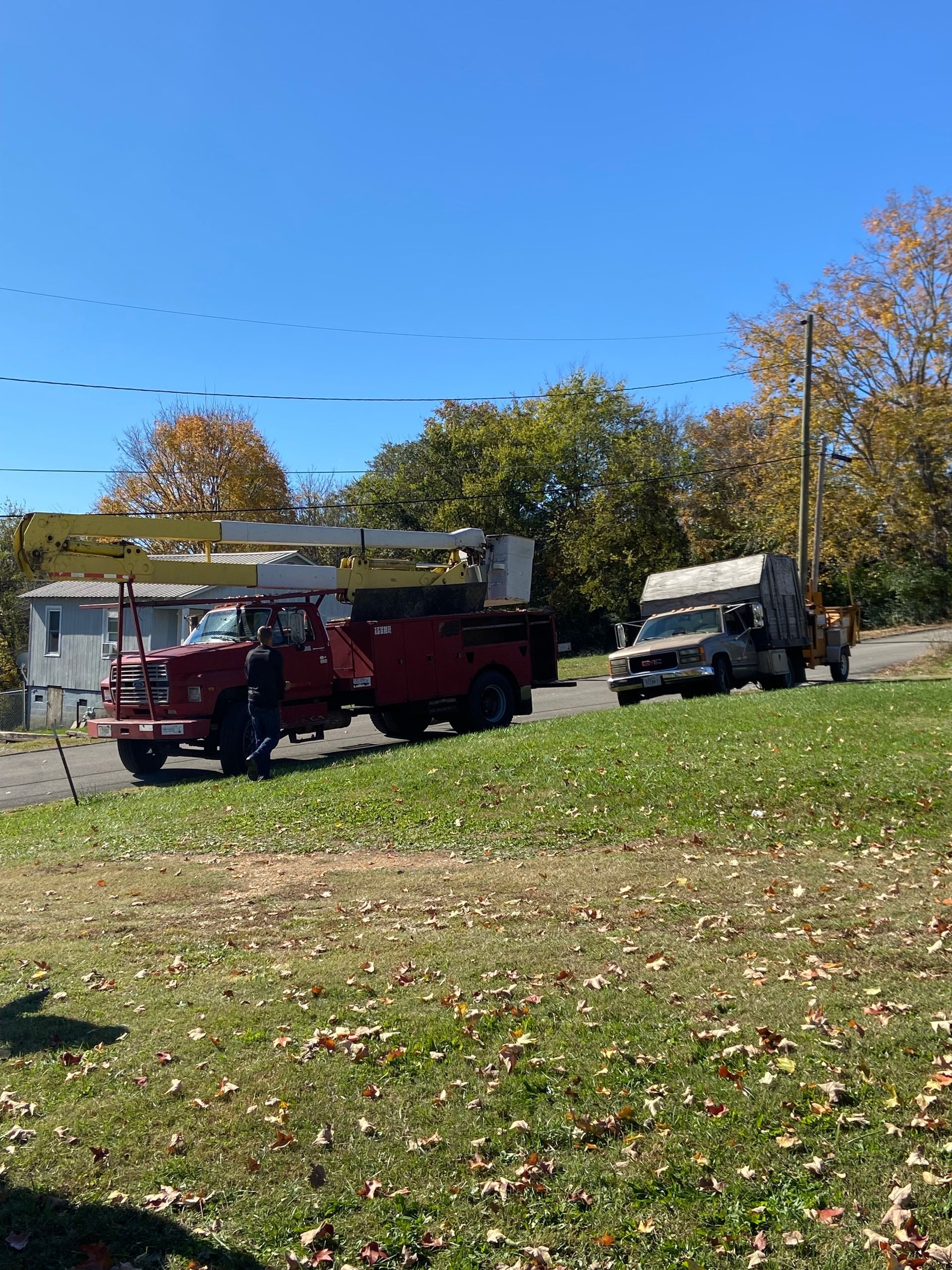 A red truck is parked on the side of the road in a grassy field.