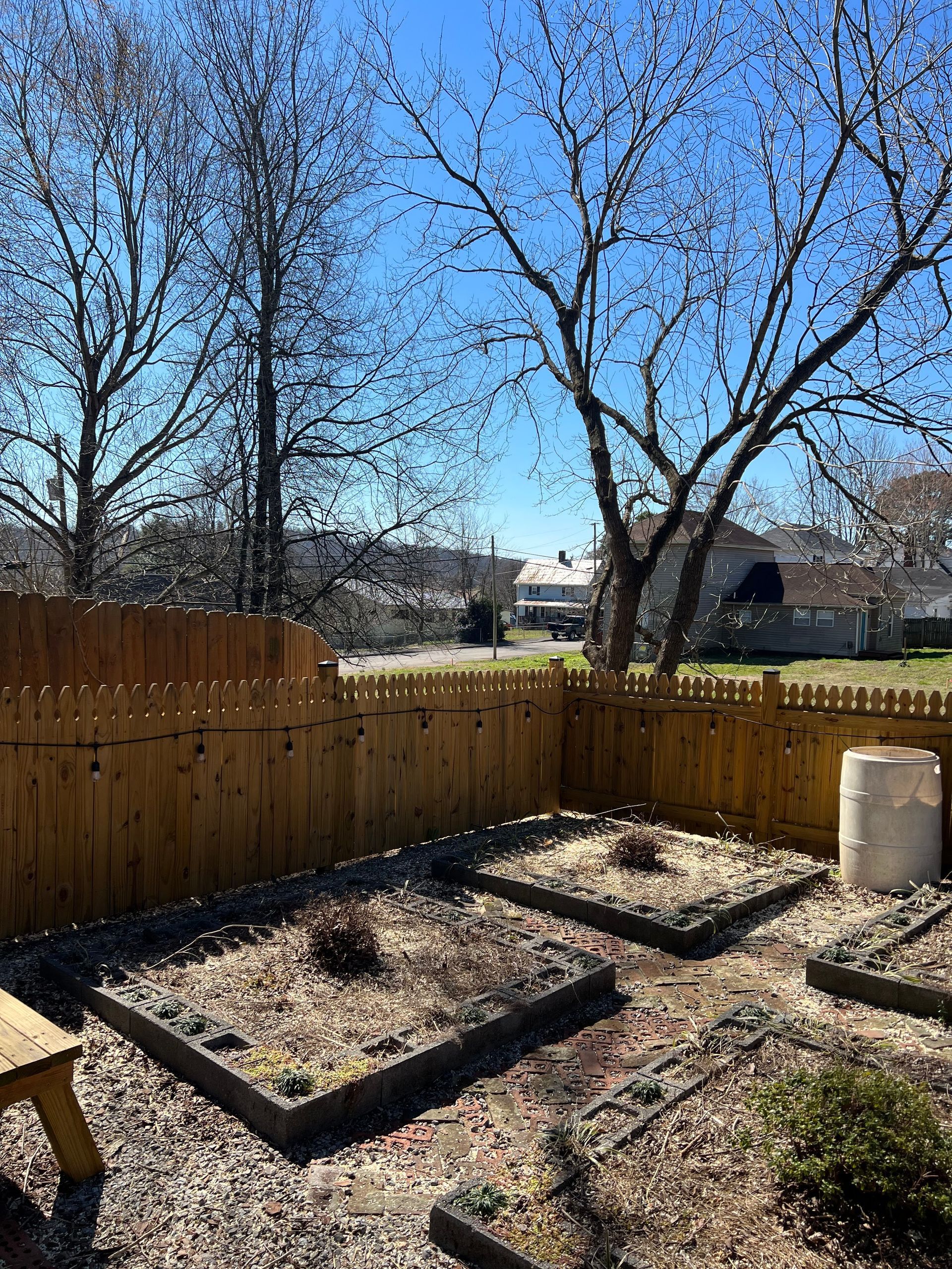 A backyard with a wooden fence and a picnic table.