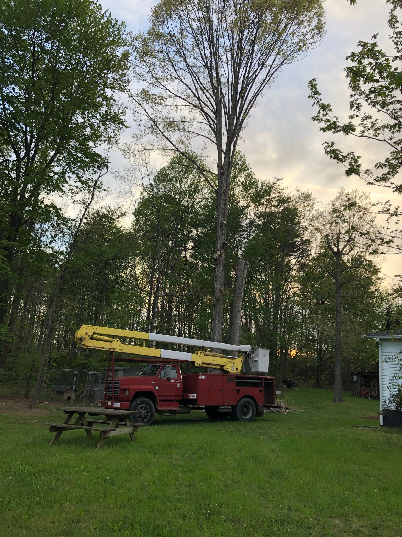 A red truck with a crane on the back is parked in a grassy field.