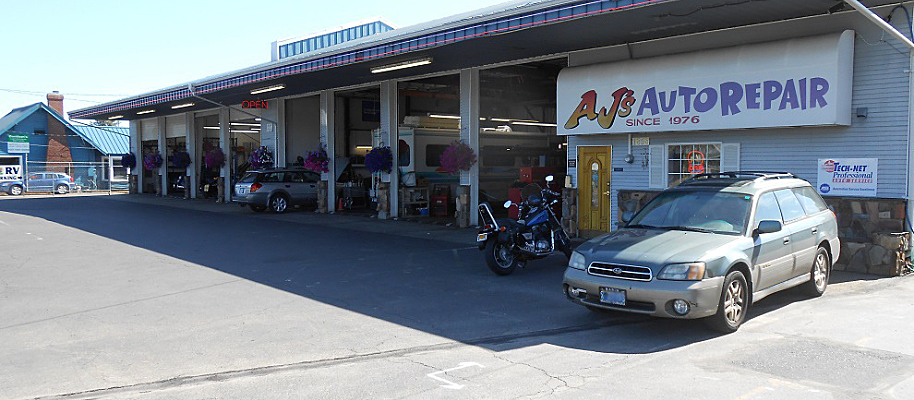 Exterior of A & B Auto Repair shop. A gray station wagon and a motorcycle are parked in front.