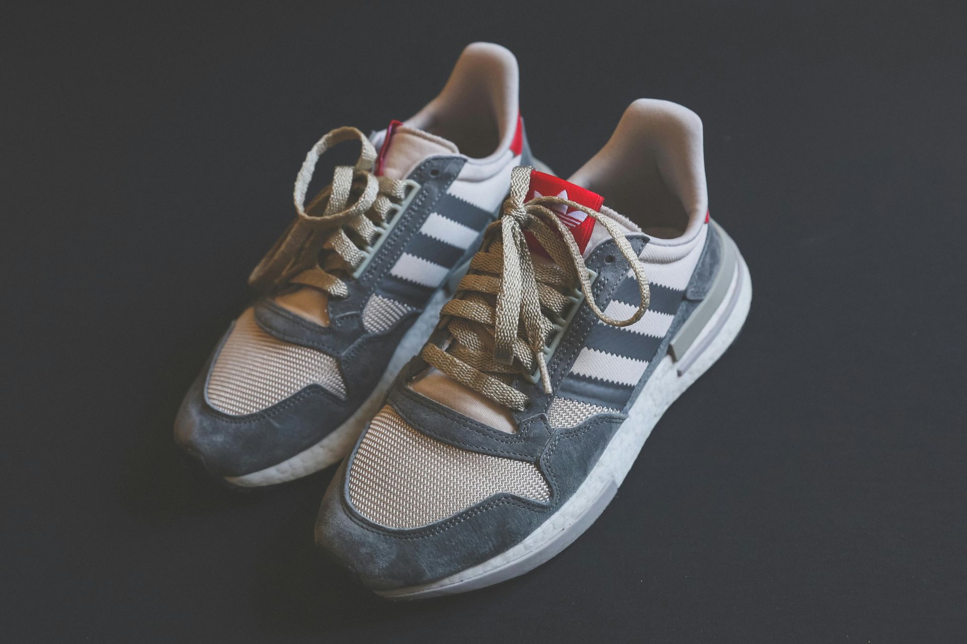 A pair of adidas sneakers are sitting on a black surface.