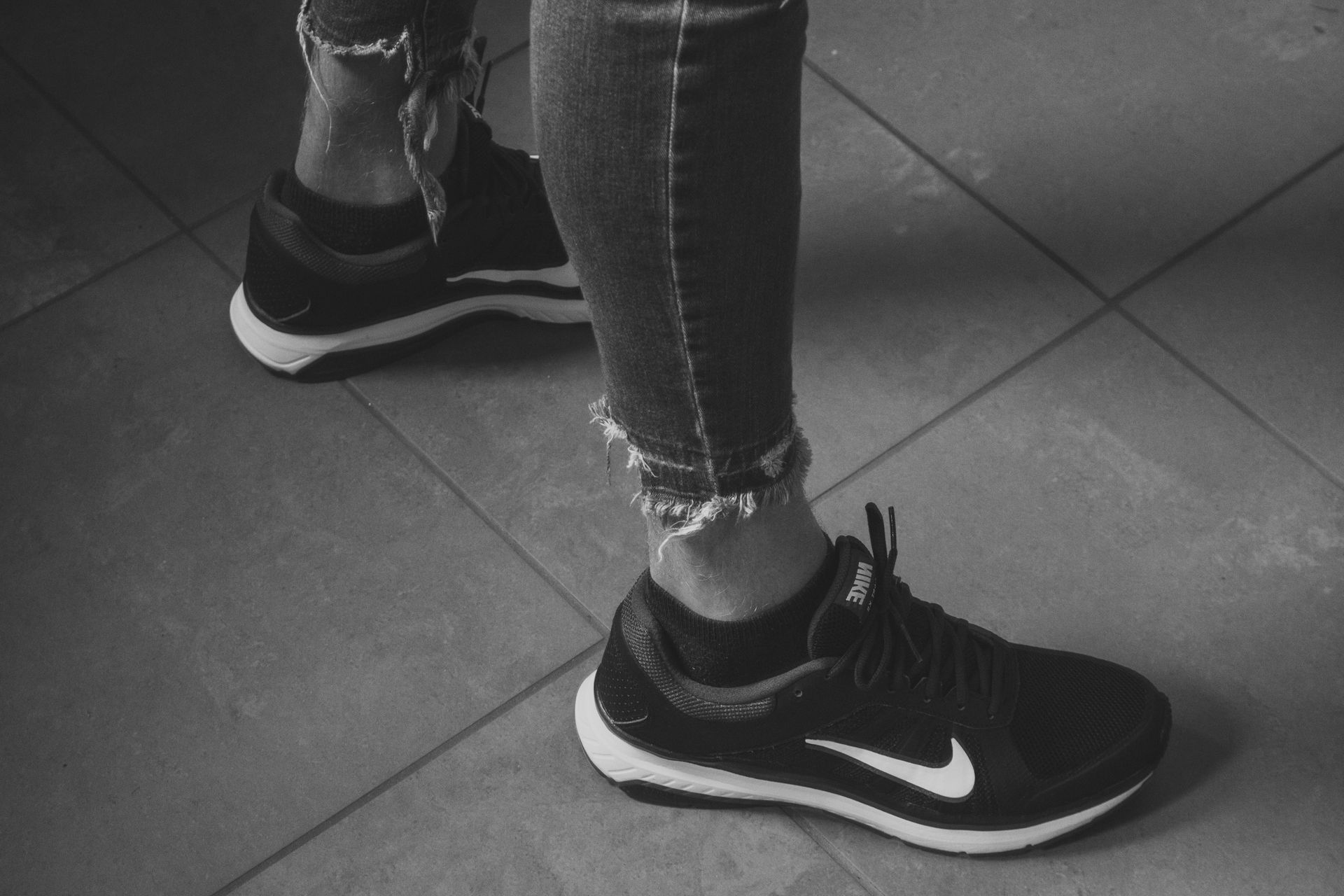 A black and white photo of a person wearing nike shoes