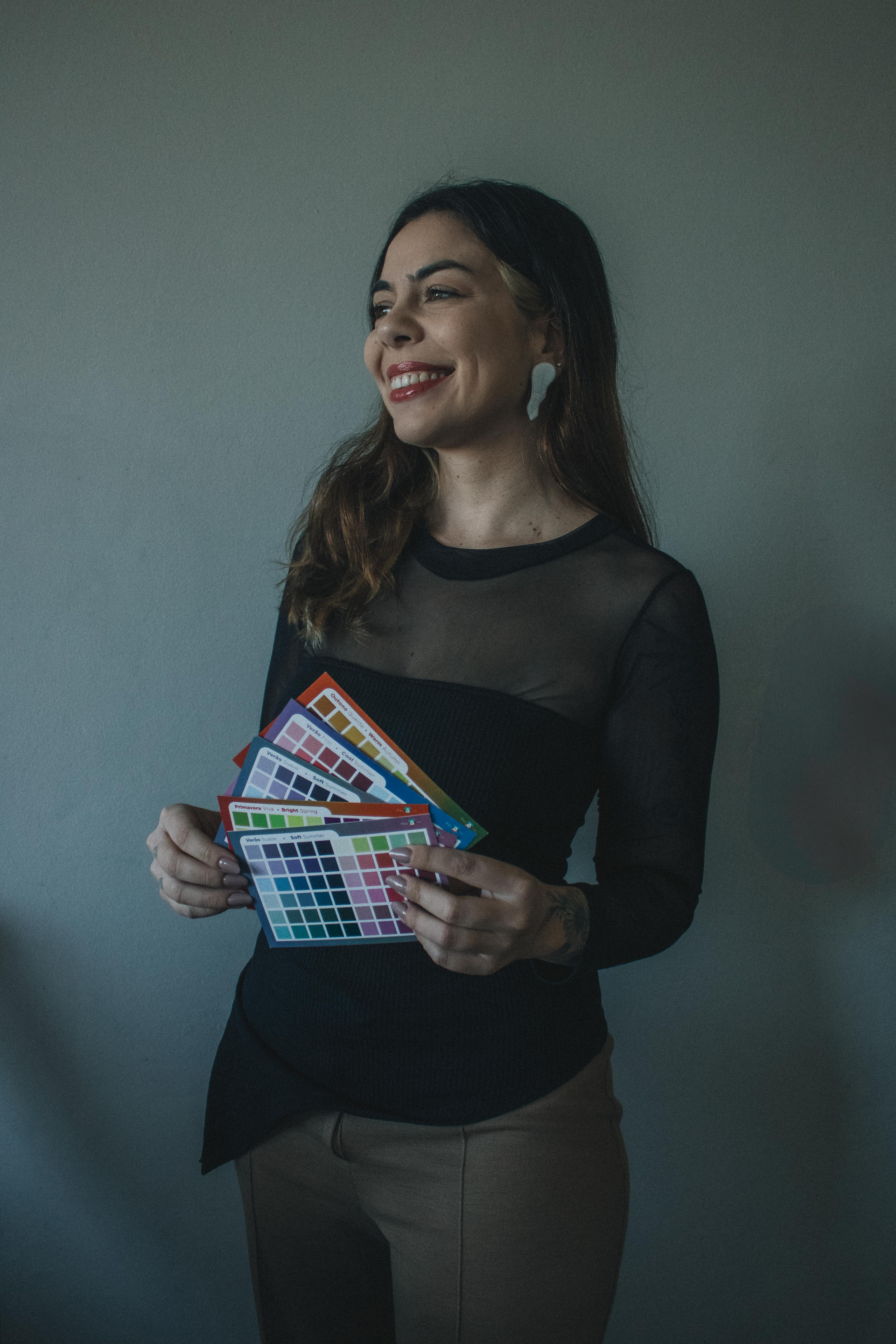 A woman is holding a bunch of stickers in her hands and smiling.