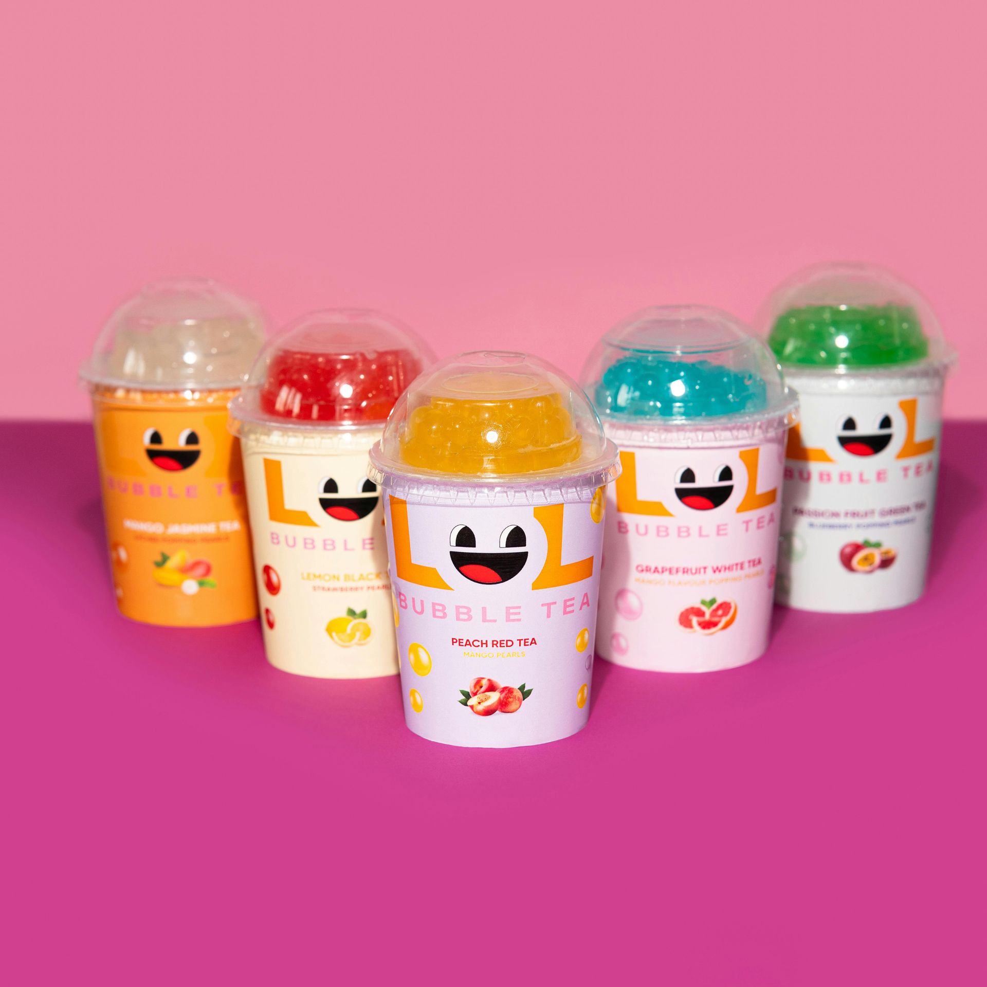 A group of lol bubble tea cups on a pink surface