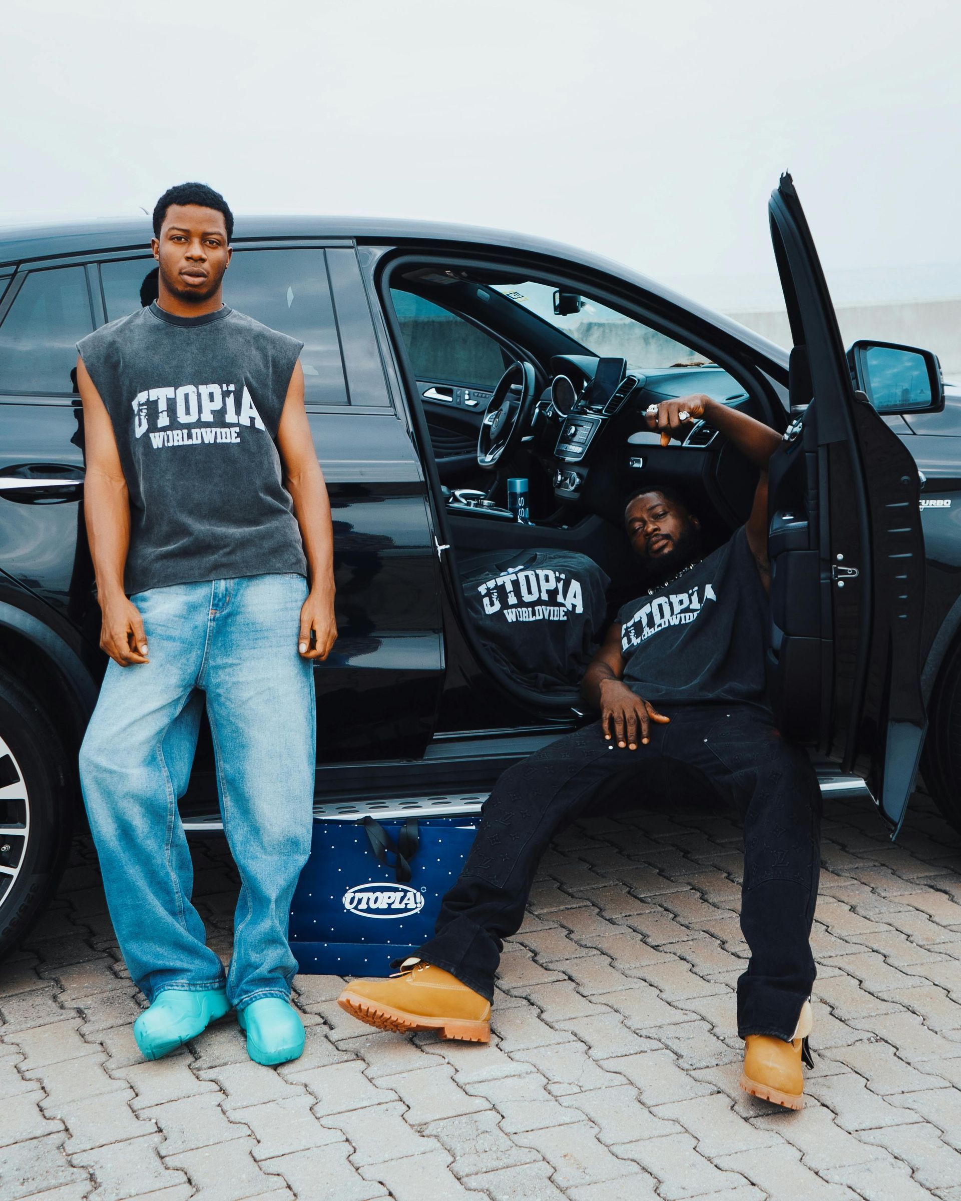 Two men standing next to a black suv with the door open