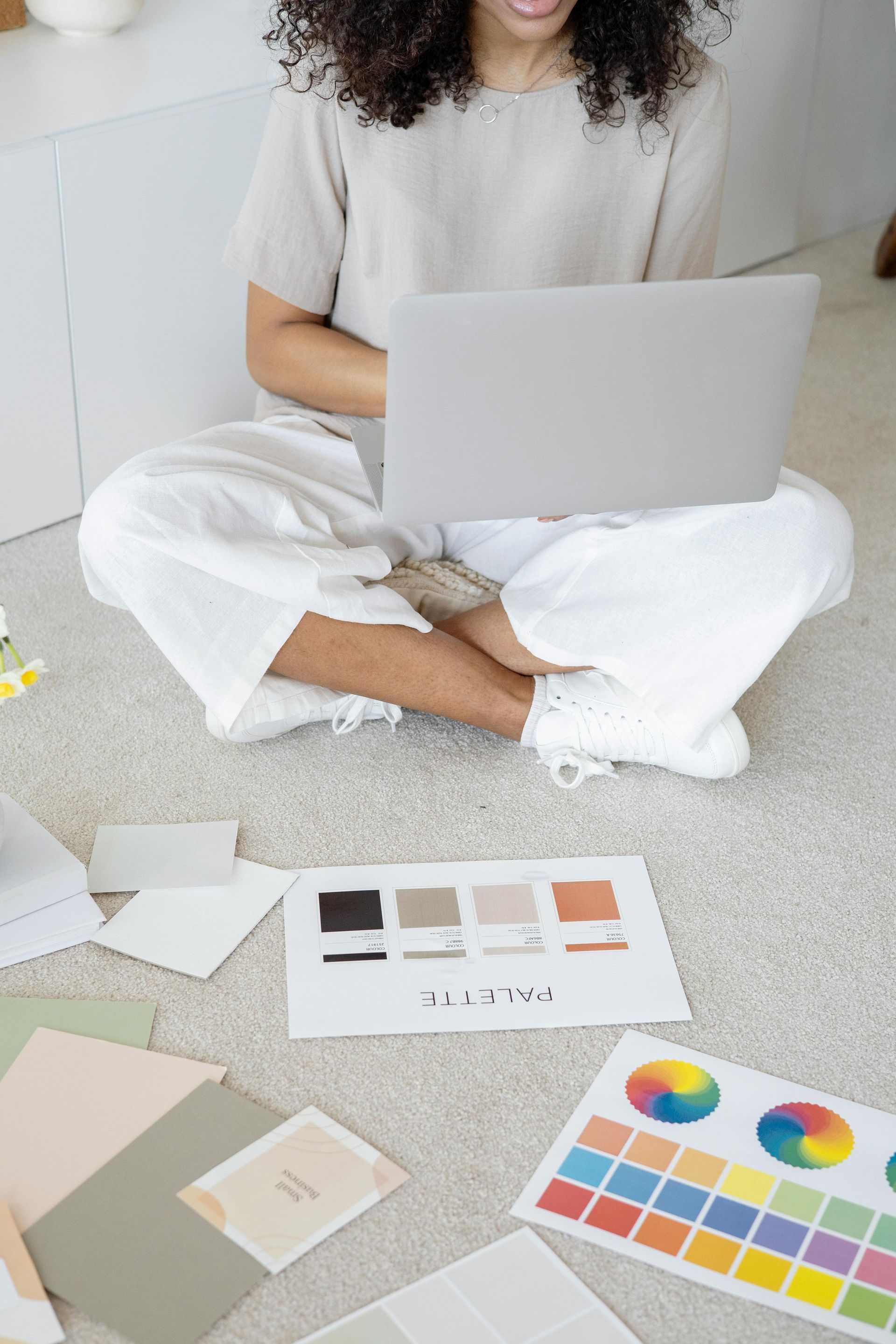 A woman is sitting on the floor using a laptop computer.