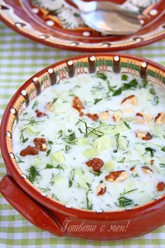 A bowl of tarator soup with a spoon in it is on a table.