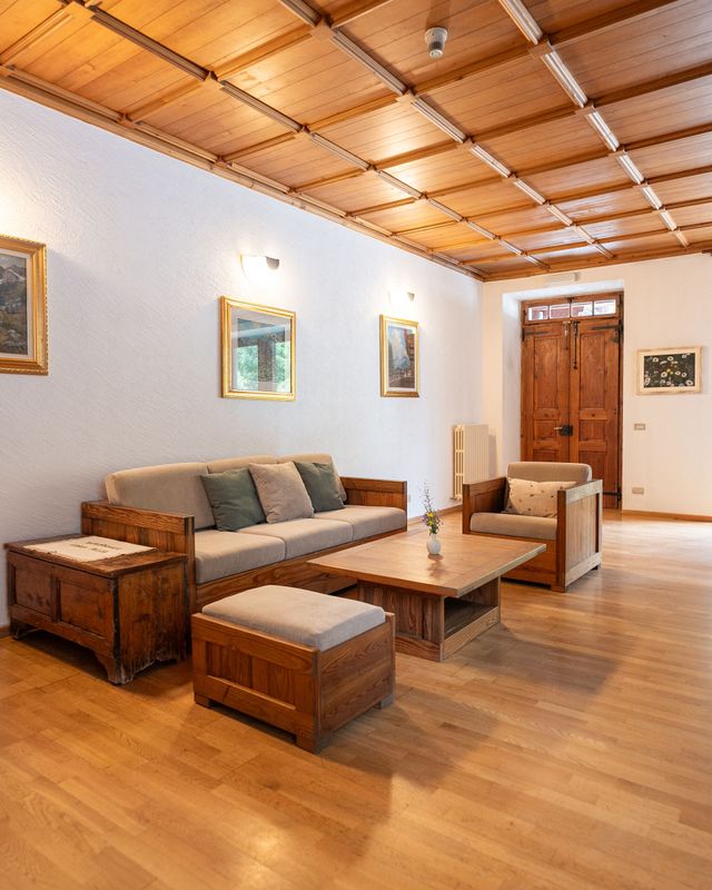 Interno del Cima Jazzi Residence — dettaglio di legno locale e pietra alpina