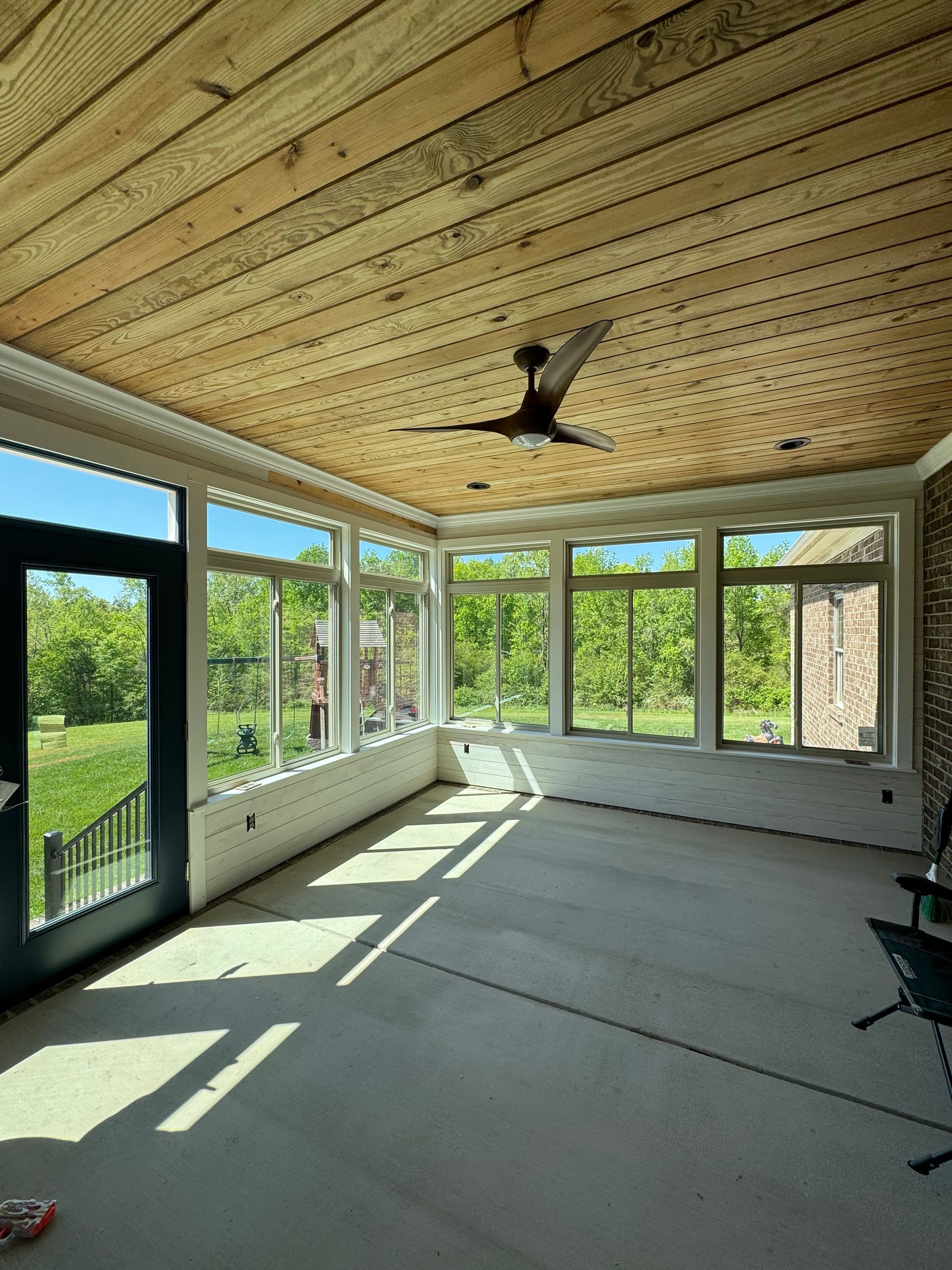 An empty room with a ceiling fan and lots of windows