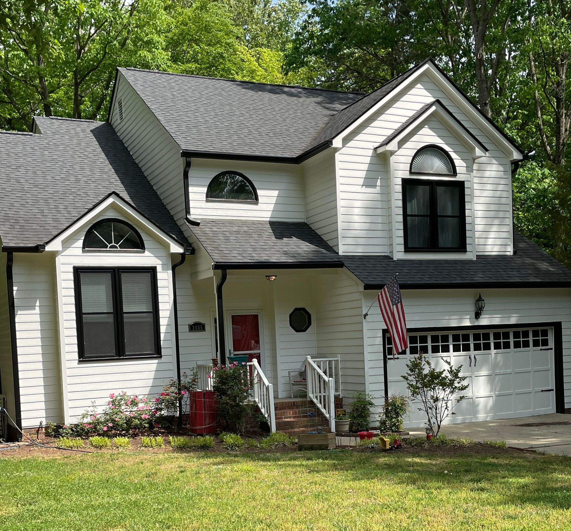 A gray house with a white garage door and a white car parked in front of it