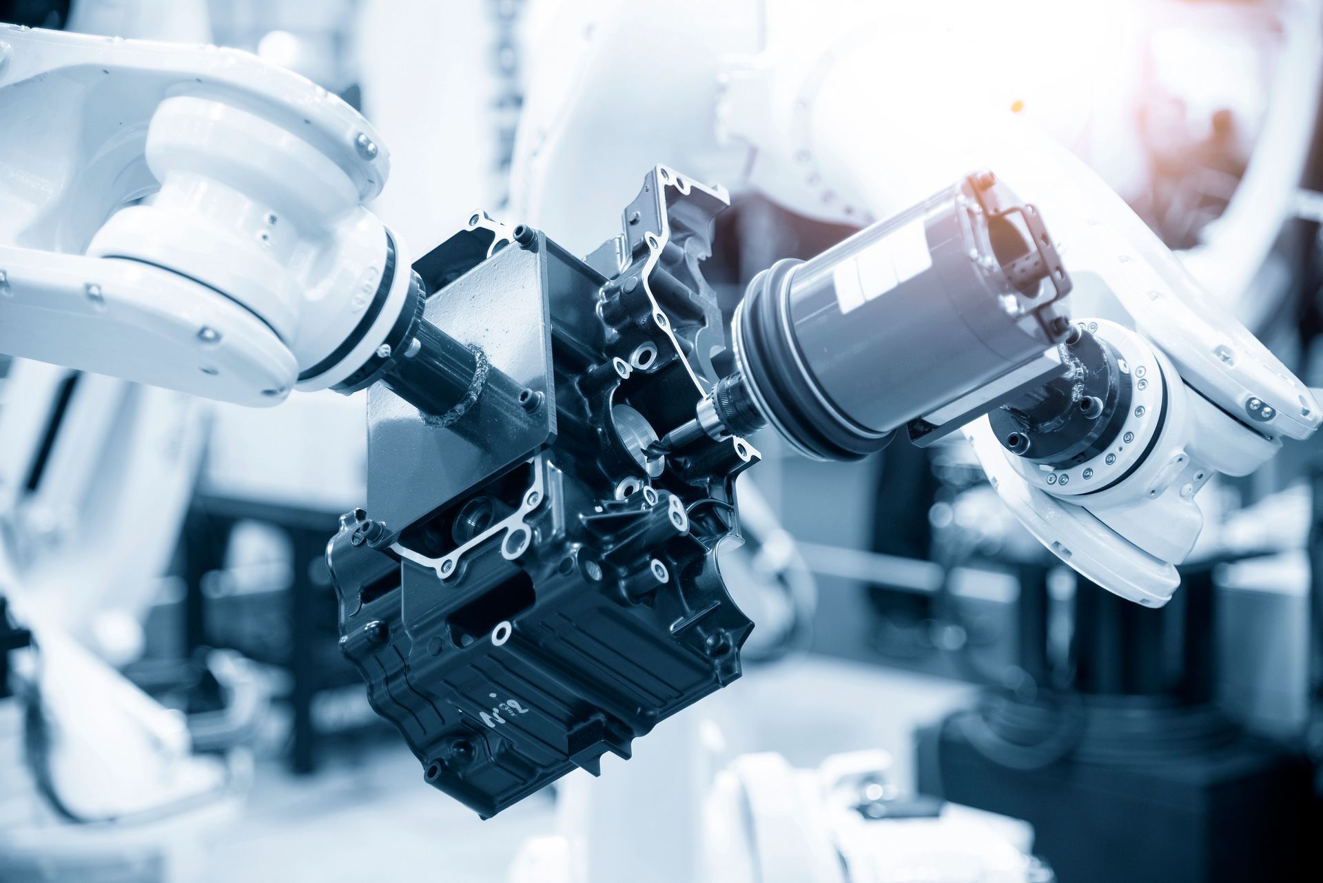 A robotic arm is working on a piece of metal in a factory.