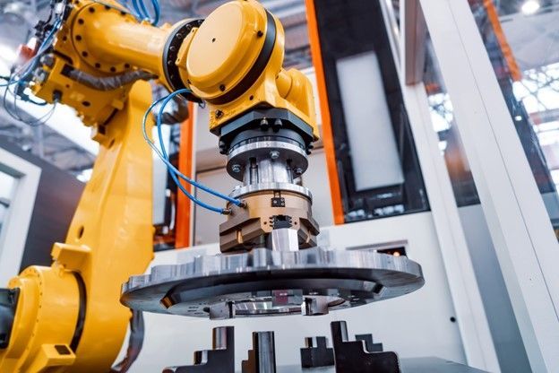 A robotic arm is working on a piece of metal in a factory.