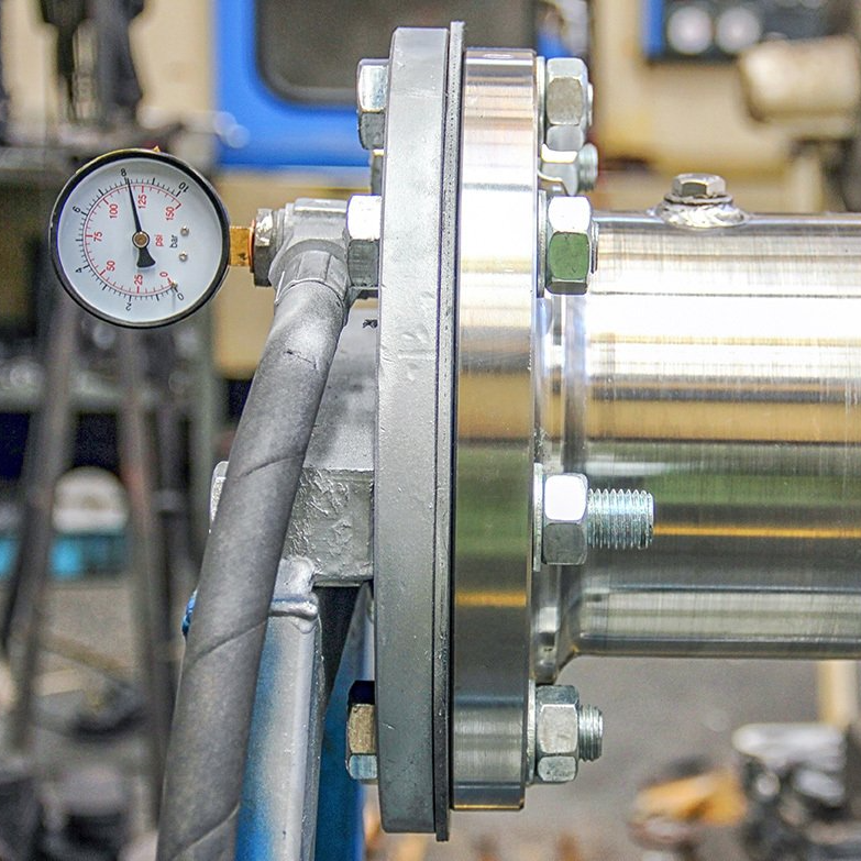 A close up of a metal pipe with a pressure gauge attached to it.