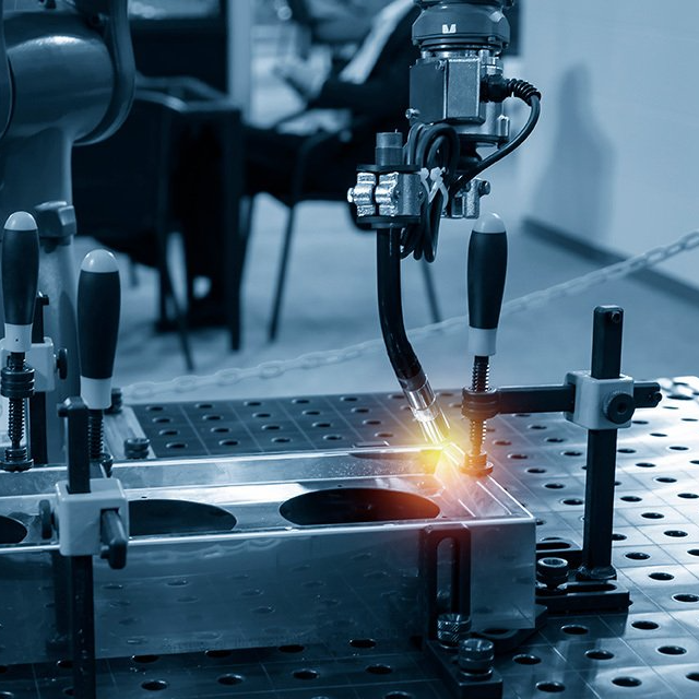 A machine is welding a piece of metal on a table.