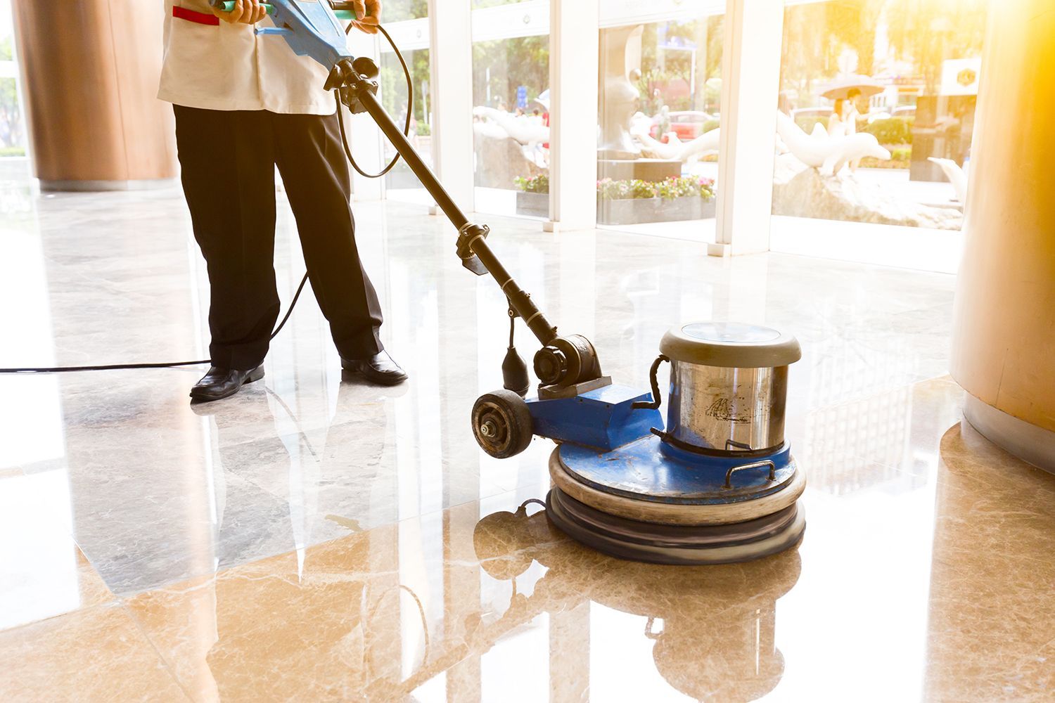 Person using a floor polisher on a glossy marble floor in a bright lobby Person using a floor polisher on a glossy marble floor in a bright lobby