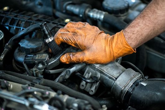 A Man Wearing Orange Gloves is Working on a Car Engine — Secure Diesel & Automotive in Ryan, QLD
