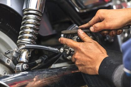 mechanic checking the suspension of a motorbike - mechnic mount Isa