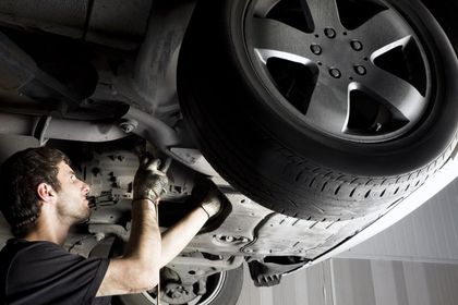 mechanic checking the bottom of a car for a roadworthy - mechnic mount Isa