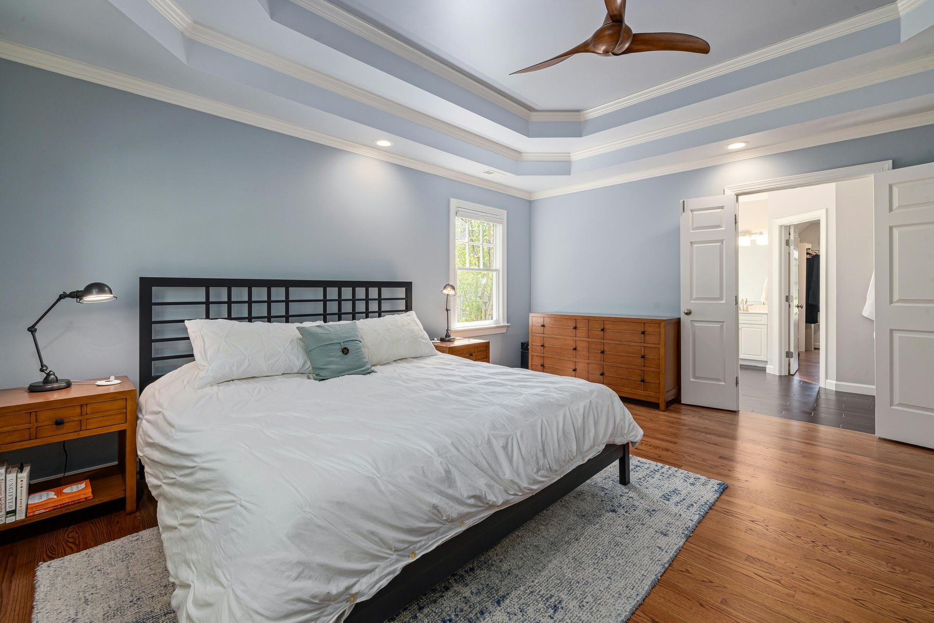 There is a ceiling fan in the bedroom with a large bed.