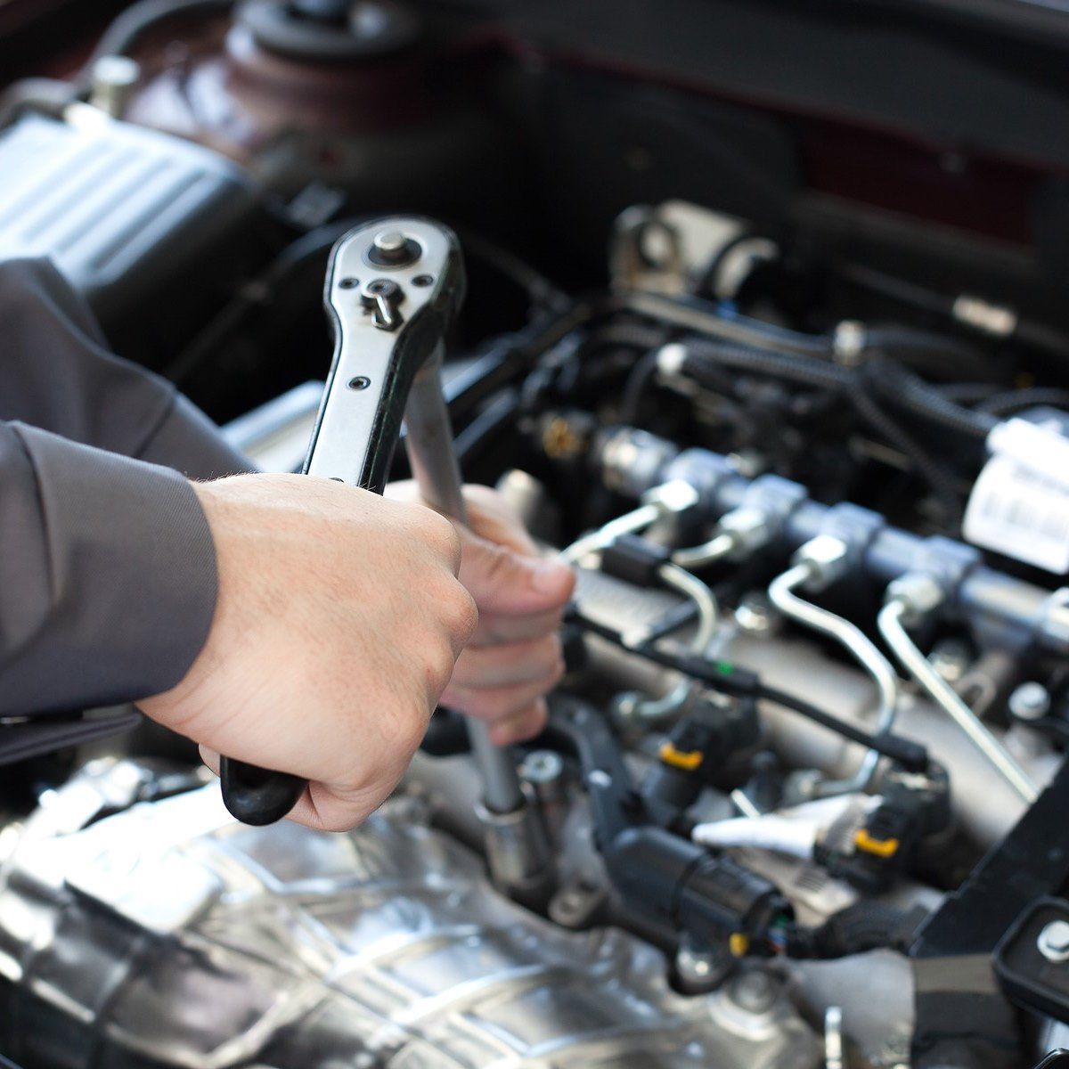 A Person is Working on a Car Engine With a Wrench — Bob Parkes Automotive in Hyde Park, QLD