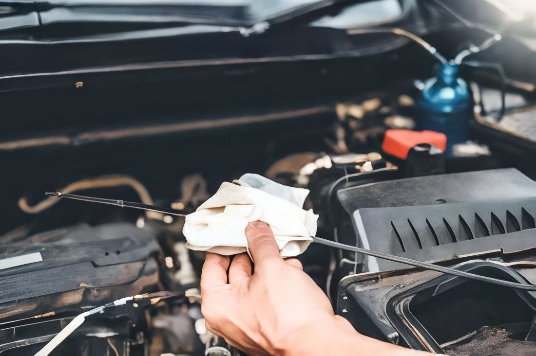 A Person is Checking the Oil Level of a Car With a Dipstick — Bob Parkes Automotive in Hyde Park, QLD