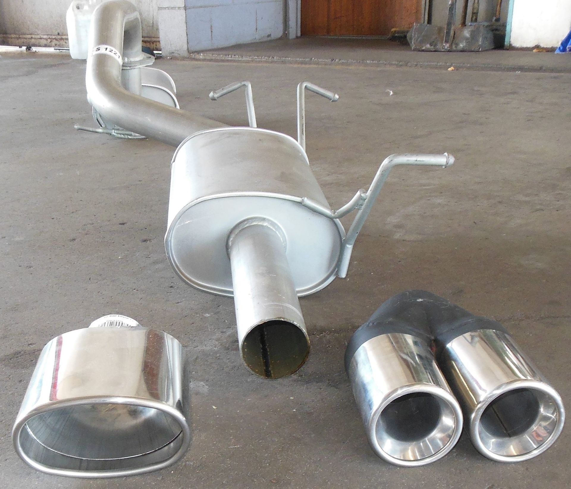 A Stainless Steel Exhaust Pipe is Laying on the Ground — Bob Parkes Automotive in Hyde Park, QLD