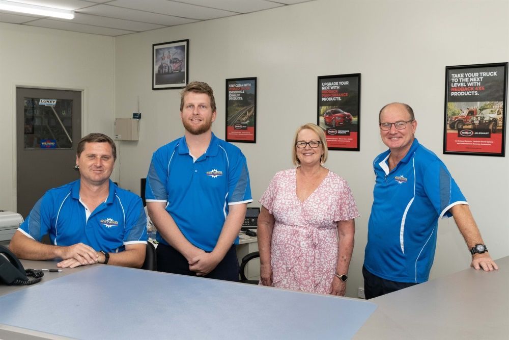 A Group of People Standing Around a Counter in a Room — Bob Parkes Automotive in Hyde Park, QLD
