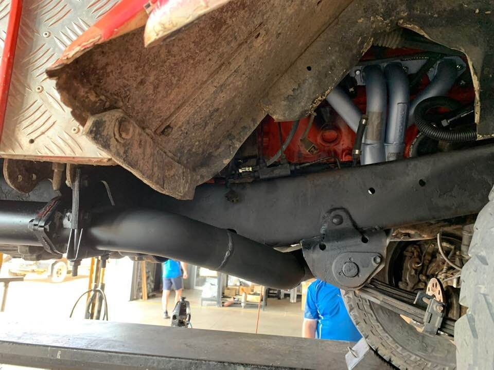 A Man in a Blue Shirt is Standing Underneath a Car — Bob Parkes Automotive in Hyde Park, QLD